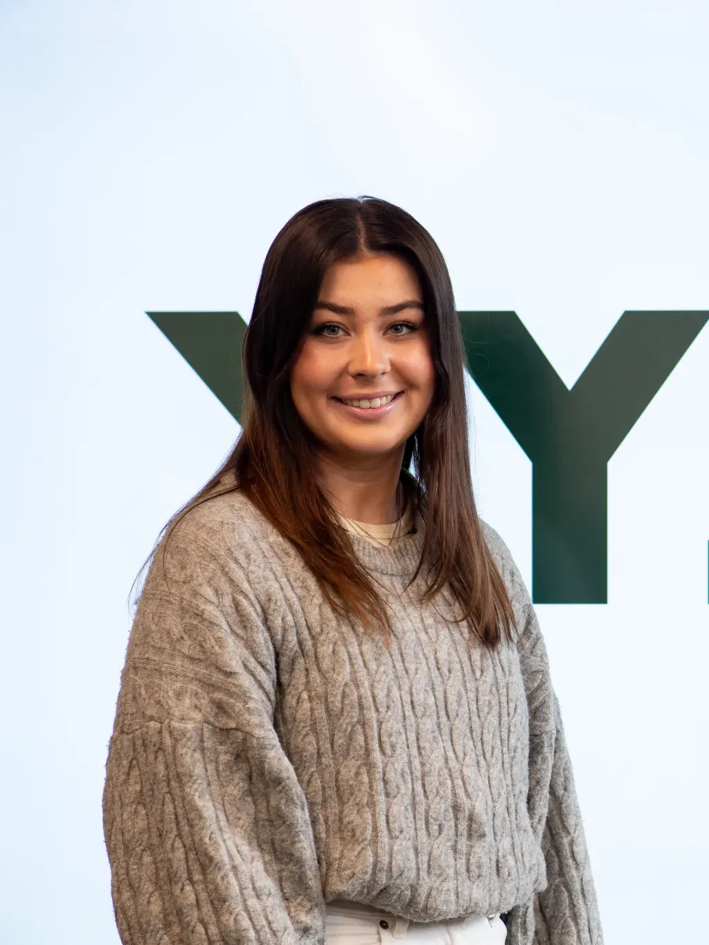 Abbie Anderson poses for a portrait. The name of her app, Clyk, is shown behind her