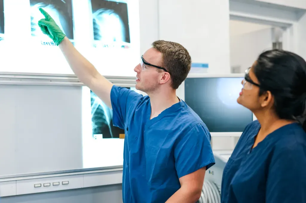 A student pointing to and explaining an x-ray image to another student