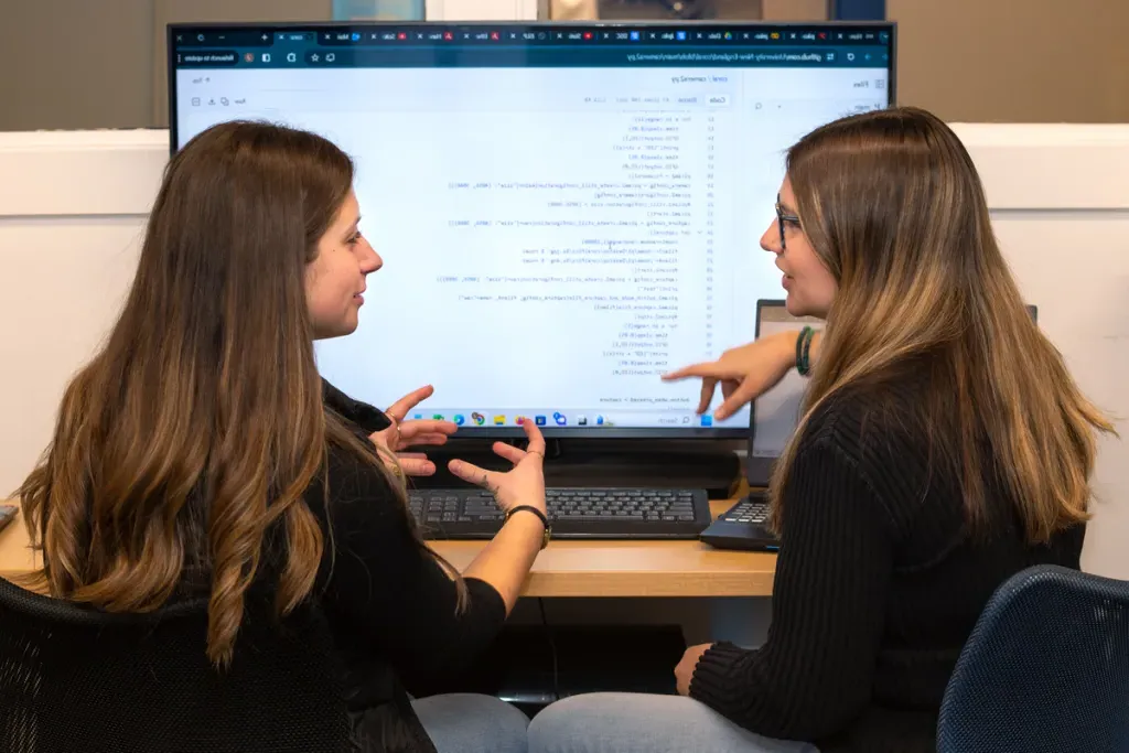 Two computer science students review computer code on a monitor