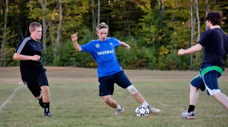 Three U N E students playing intramural soccer