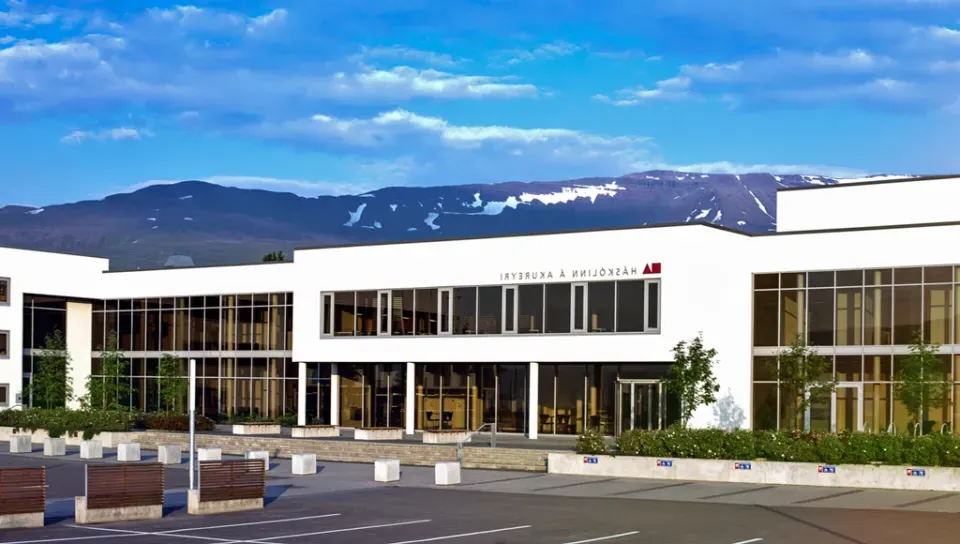 A white building with a lot of windows in front of a mountainscape and blue skies