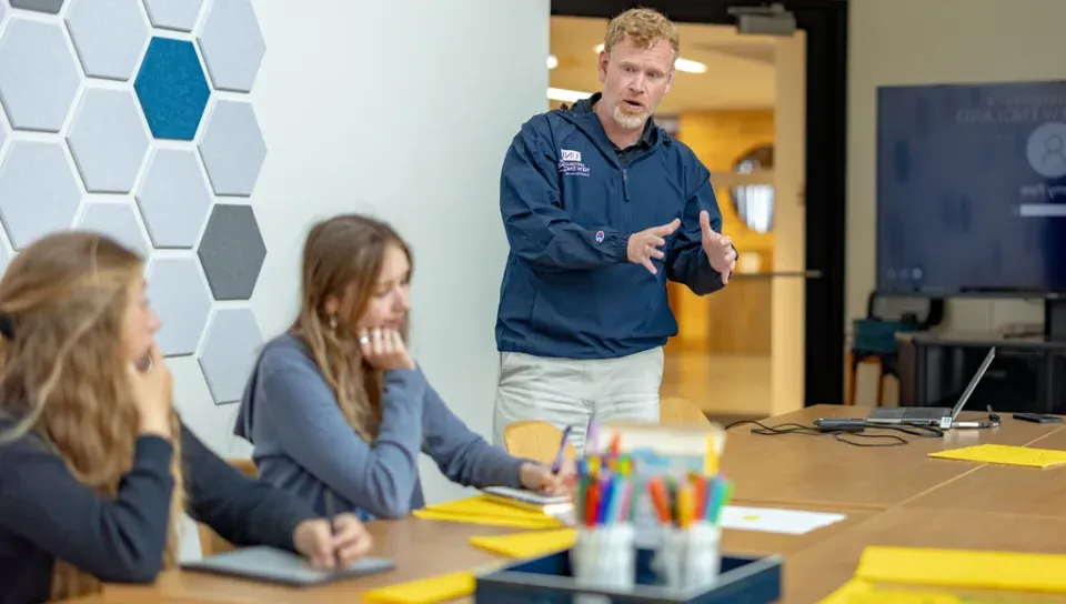 A group of students listen to a professor in a classroom