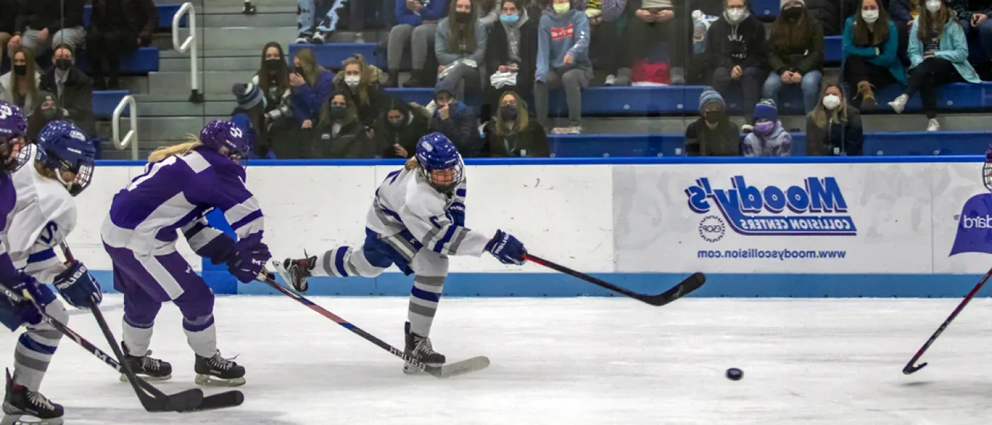 Women's hockey players going after the puck during a game