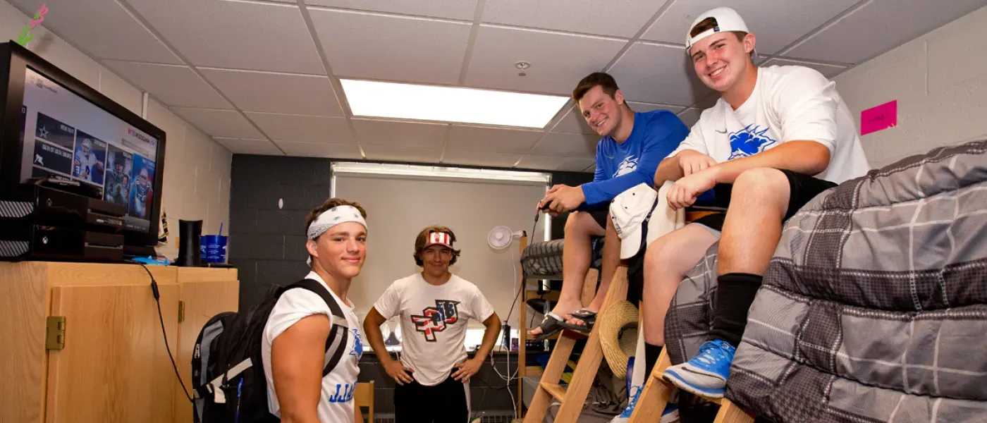 Four students taking a break from moving into their dorm room