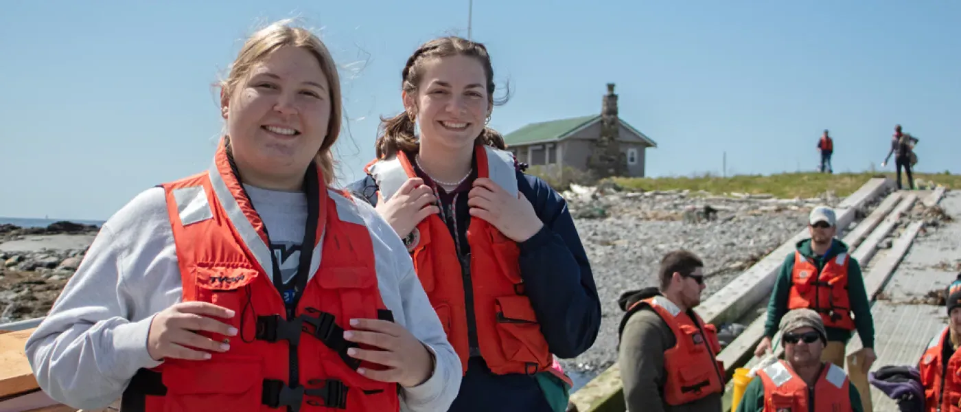 Students in life vests walk up to the lighthouse on Ram Island