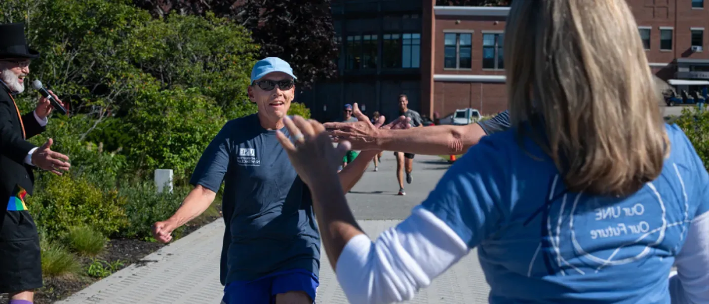 U N E employees high-fiving during the annual fall assembly fun run