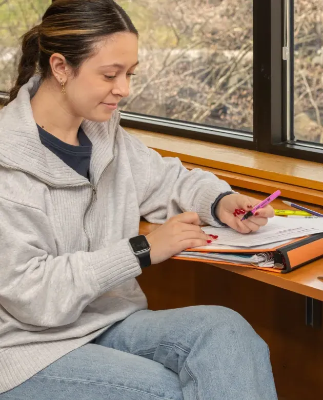 A student uses a pink highlighter on their notes