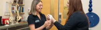 An athletic training student practices wrapping the wrist of another student