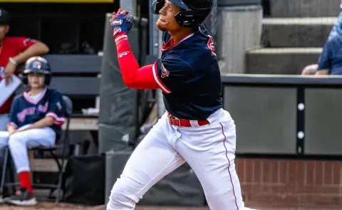 A baseball player follows through with a swing at Hadlock Field in Portland