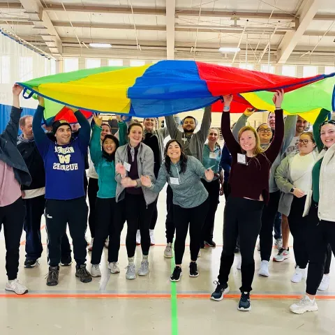 students holding up colorful parachute