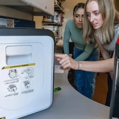 Two students operate a 3D printer